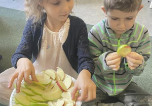 dzieci częstują się plasterkami kolorowych jabłek